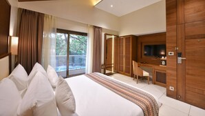 A hotel room with a large bed, a desk with a chair, a television, and a wardrobe. - Arova Woods Zinc Journey (Mawal)