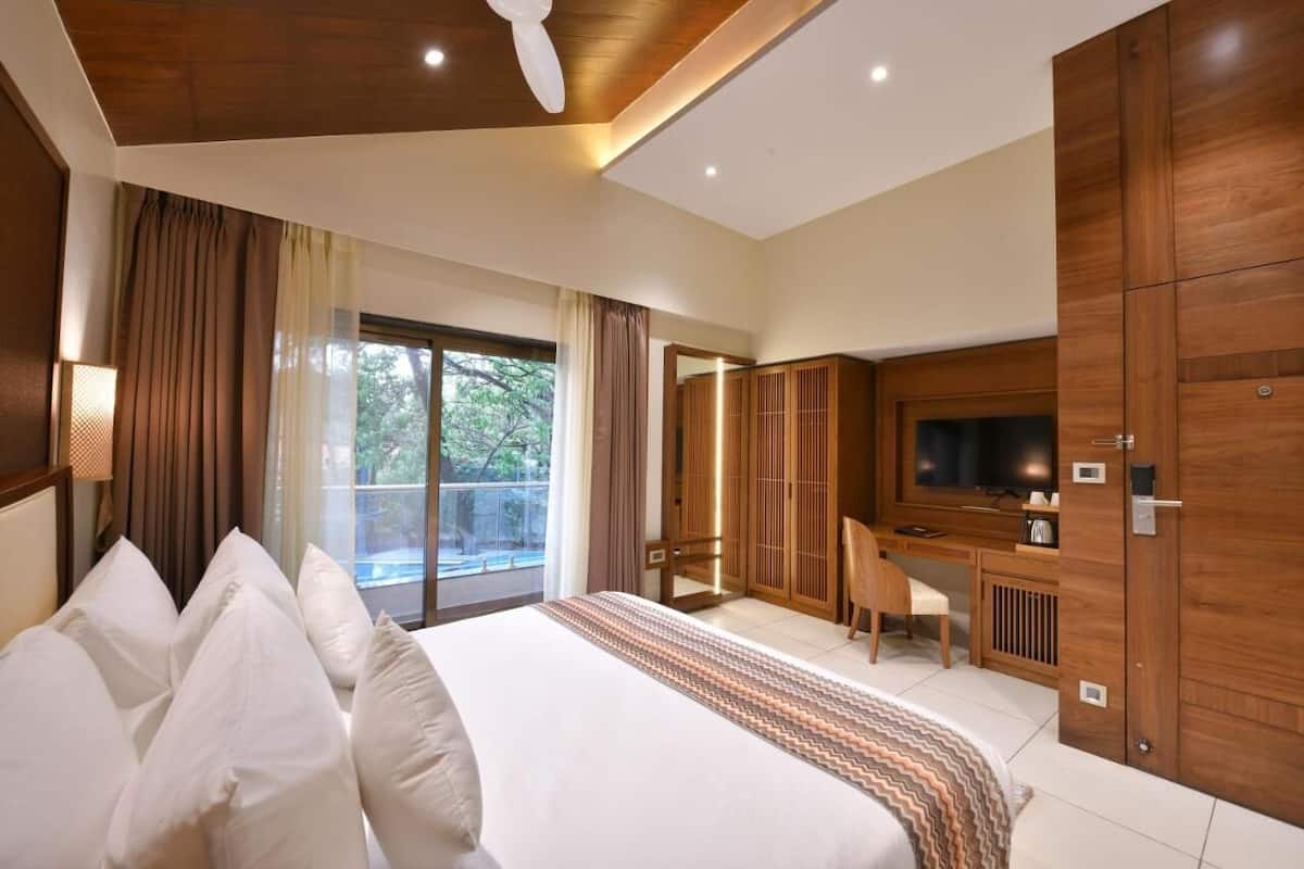 Una habitación de hotel con una cama grande, un escritorio con una silla, un televisor y un armario.