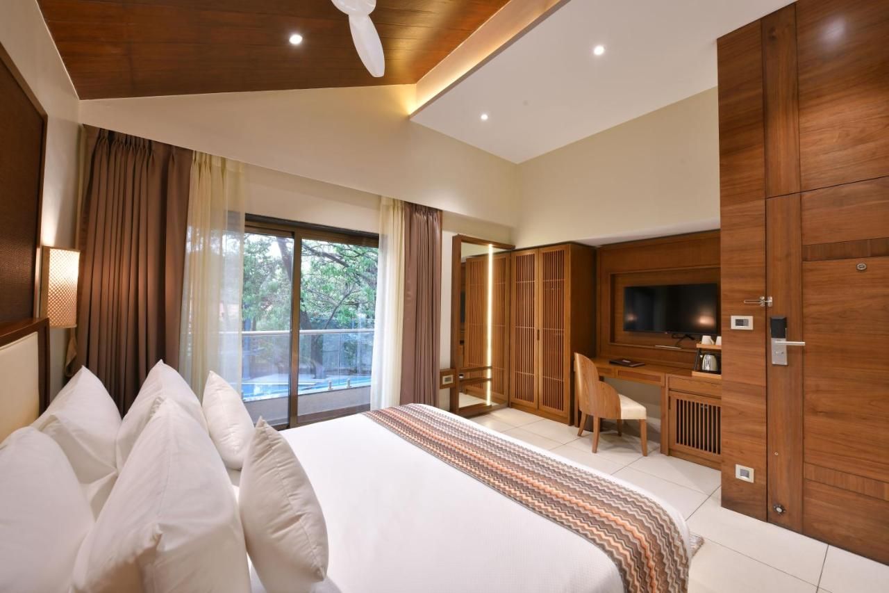 Une chambre d’hôtel avec un grand lit, un bureau avec une chaise, une télévision et une armoire.