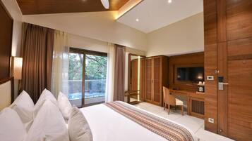 A hotel room with a large bed, a desk with a chair, a television, and a wardrobe.