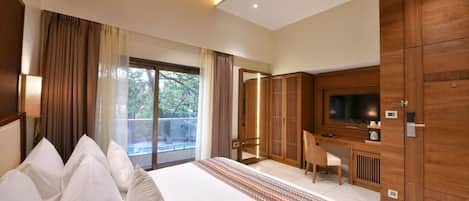 A hotel room with a large bed, a desk with a chair, a television, and a wardrobe.