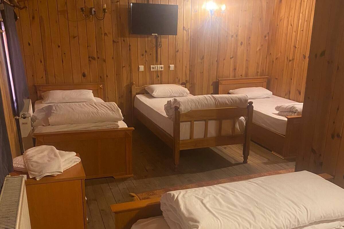 A wooden cabin room with four beds, a television, and a heater.