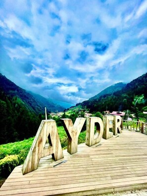 A wooden boardwalk with large wooden letters spelling 'AYDER' against a mountainous backdrop. - Vesile Otel (Çamlıhemşin)