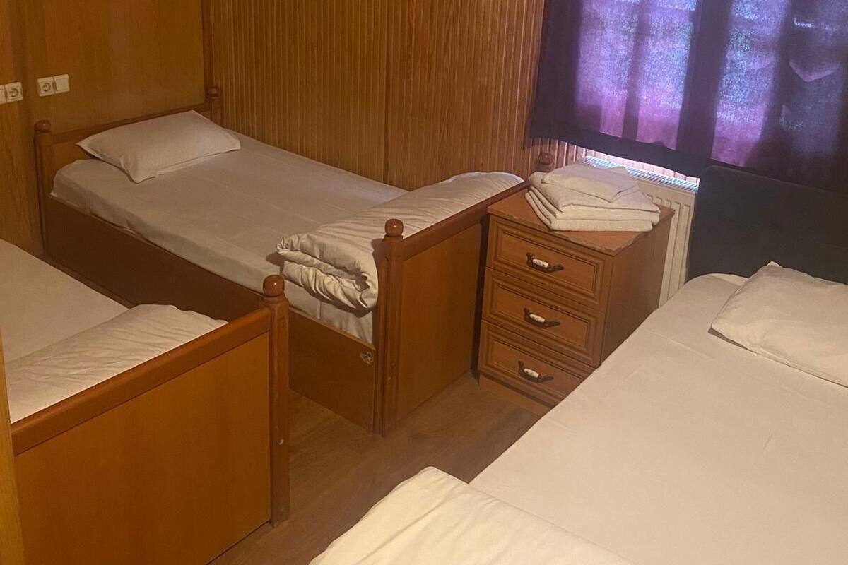 A room with three wooden beds, a wooden dresser, and a window with curtains.