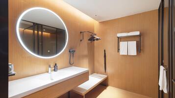 Un baño moderno con un espejo grande, un lavabo, una ducha y un perchero para toallas.
