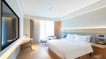 Una habitación de hotel moderna con una cama grande, un escritorio, una silla y una mesita.