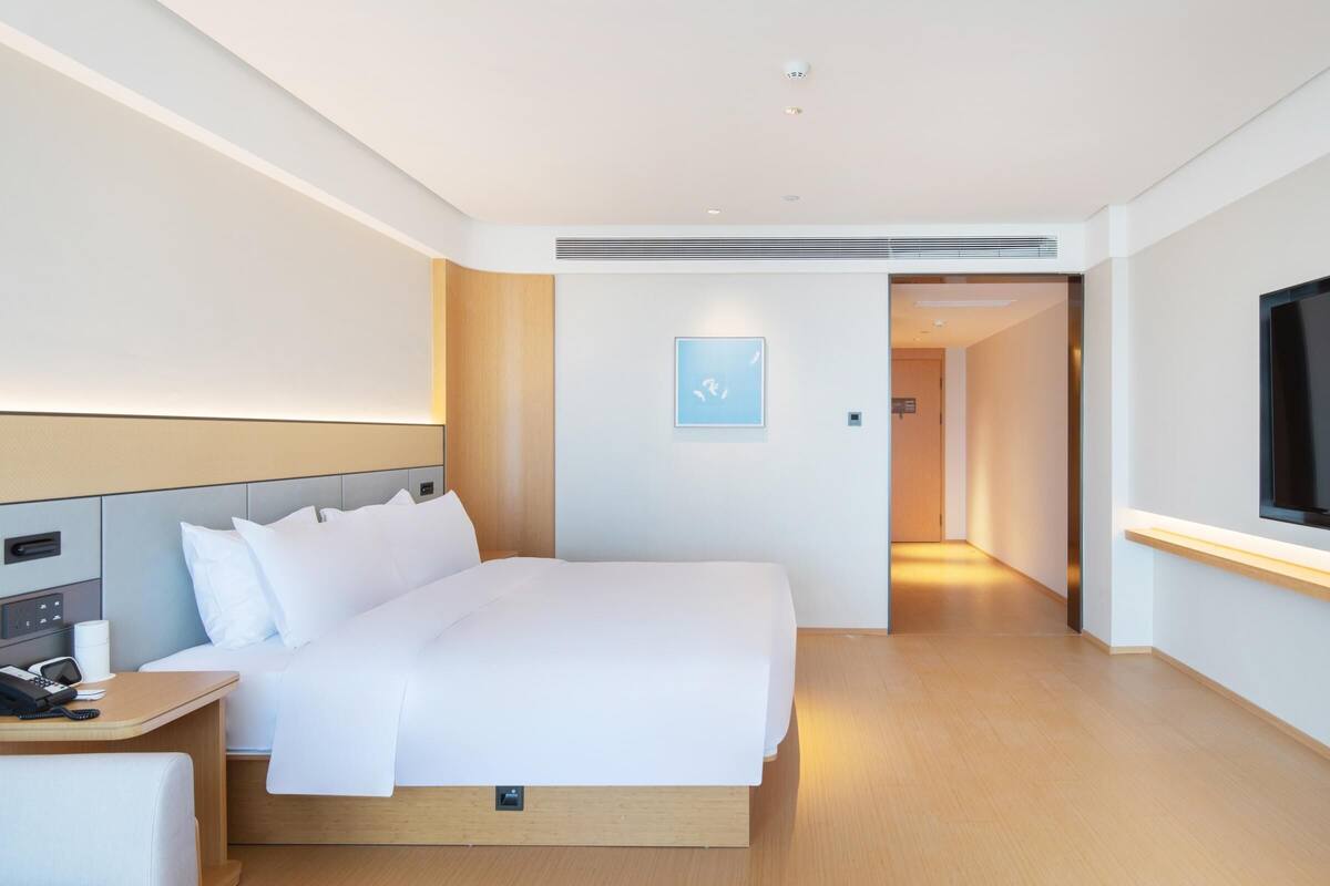 Et moderne hotelværelse med en stor seng, et natbord og et fladskærms-tv.