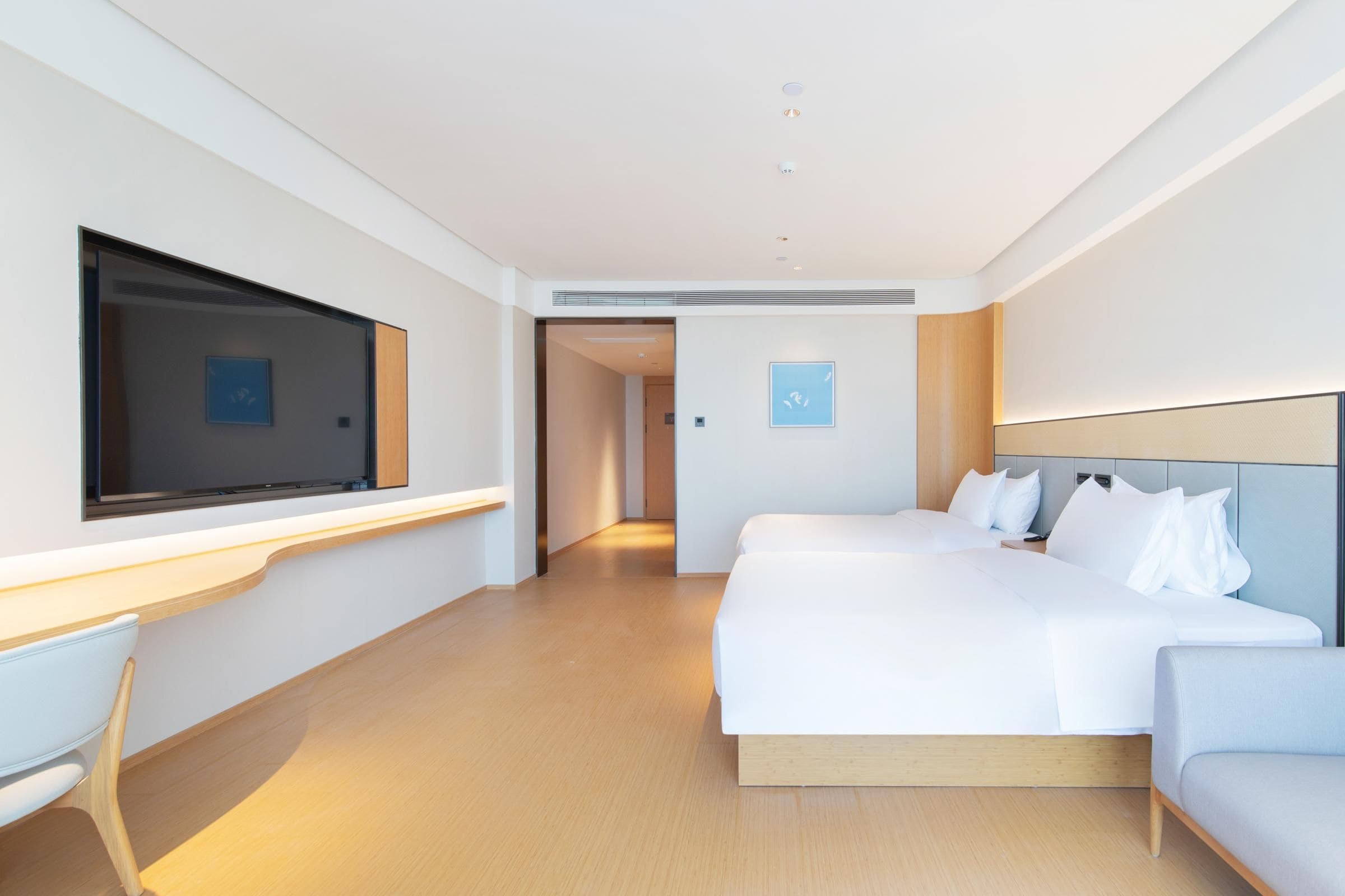 Una habitación de hotel moderna con una cama grande, un escritorio y un televisor.