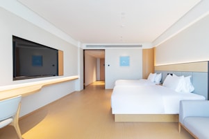 A modern hotel room with a large bed, a desk, and a TV.