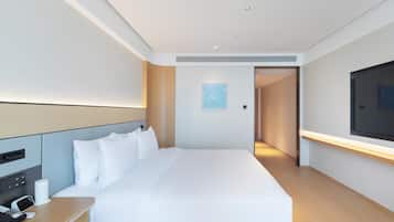 A modern hotel room with a large bed, bedside table with a phone, and a TV mounted on the wall.