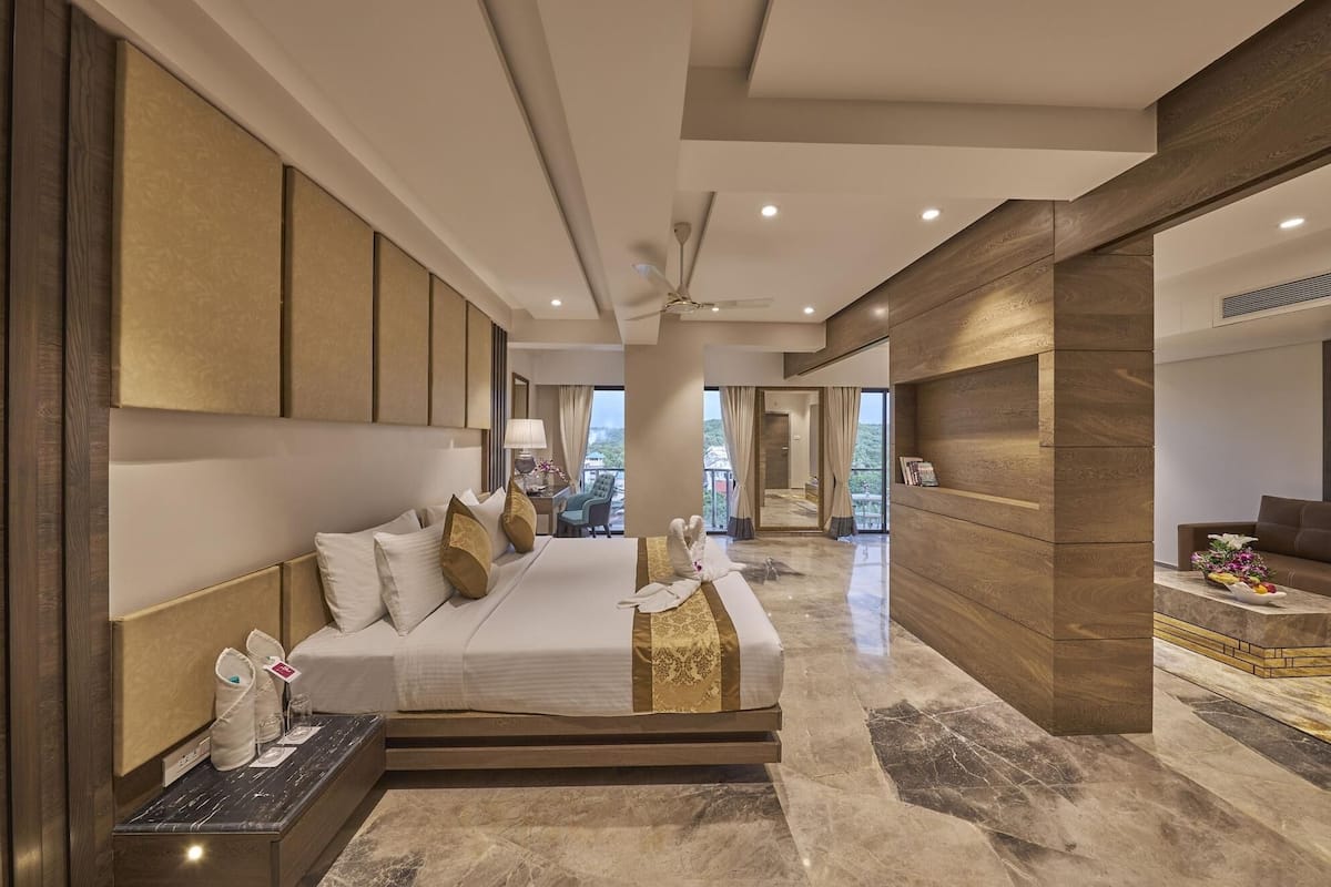 A modern hotel room with a large bed, a desk, and a view of the outdoors.