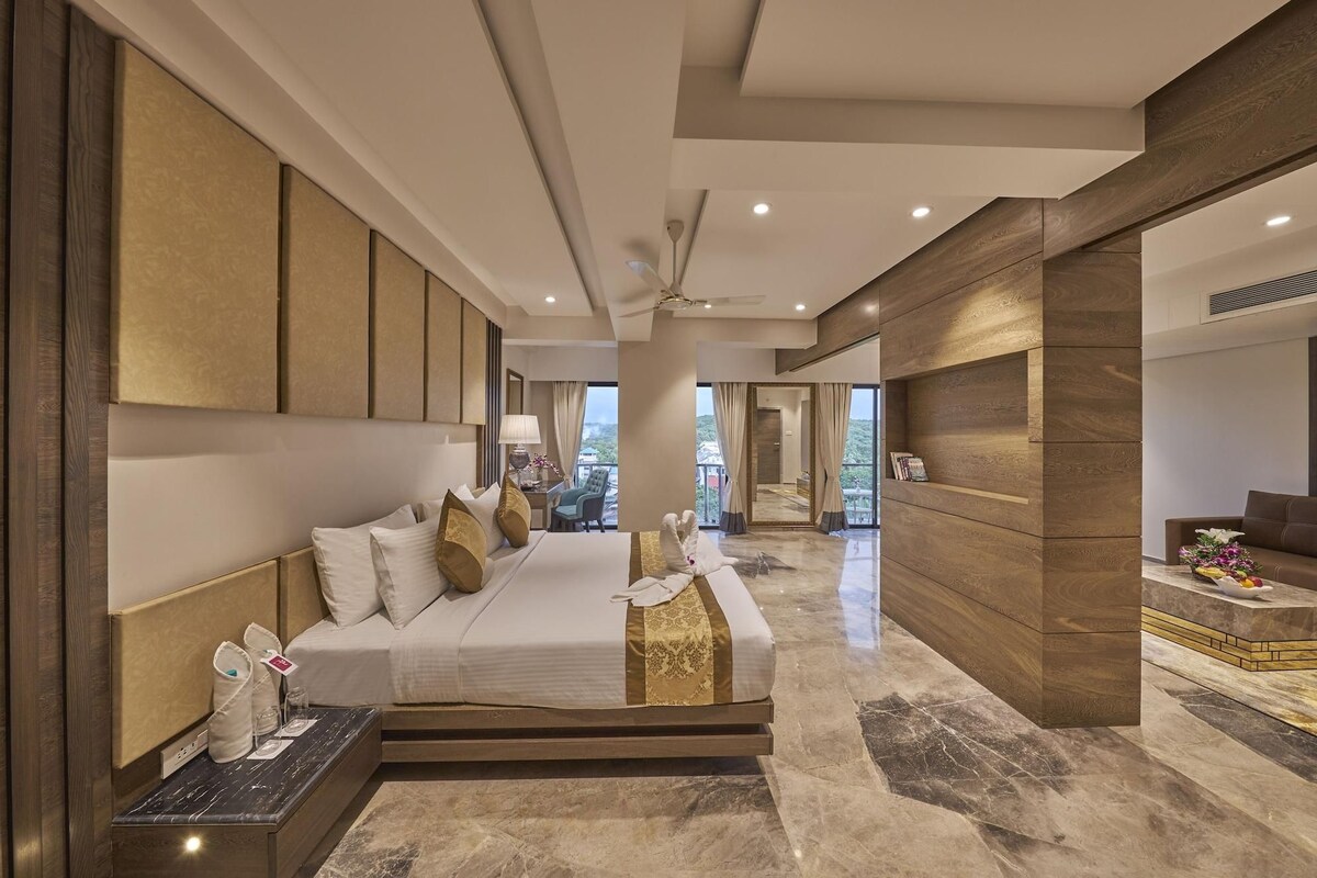 A modern hotel room with a large bed, a desk, and a view of the outdoors.