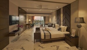 A modern bedroom with a large bed, a TV, a desk, and a balcony with a view. - Regenta Central Imperial Candolim (Candolim)