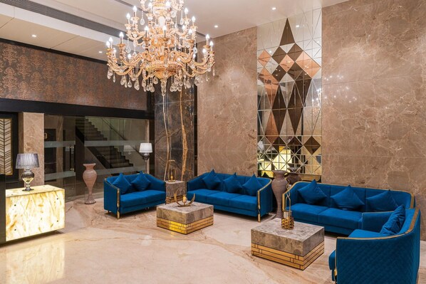 A lobby with a chandelier, blue sofas, marble flooring, and a geometric wall design. - Regenta Central Imperial Candolim (Candolim)