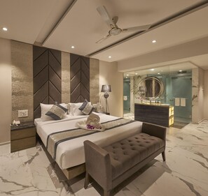 A modern bedroom with a bed, bedside table, lamp, and a ceiling fan. - Regenta Central Imperial Candolim (Candolim)