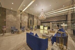 A modern lobby with marble walls, a reception desk, seating areas, and a chandelier. - Regenta Central Imperial Candolim (Candolim)