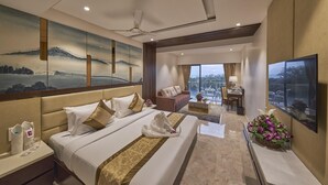 A hotel room with a bed, a sofa, a desk, and a TV. - Regenta Central Imperial Candolim (Candolim)