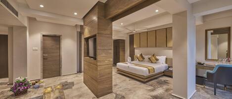 A modern hotel room with a large bed, a vanity with a mirror, and a seating area with a table.
