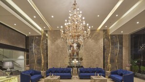 A luxurious lobby with a grand chandelier, marble walls, and blue sofas. - Regenta Central Imperial Candolim (Candolim)
