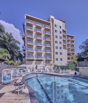 A hotel with a pool, multiple balconies, and outdoor seating areas. - Regenta Central Imperial Candolim (Candolim)
