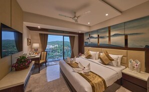 A hotel room with a large bed, a desk, a chair, a TV, and a balcony with a view. - Regenta Central Imperial Candolim (Candolim)