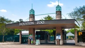 La entrada al zoológico de Houston, con un letrero, una puerta con la etiqueta '3' y un basurero.