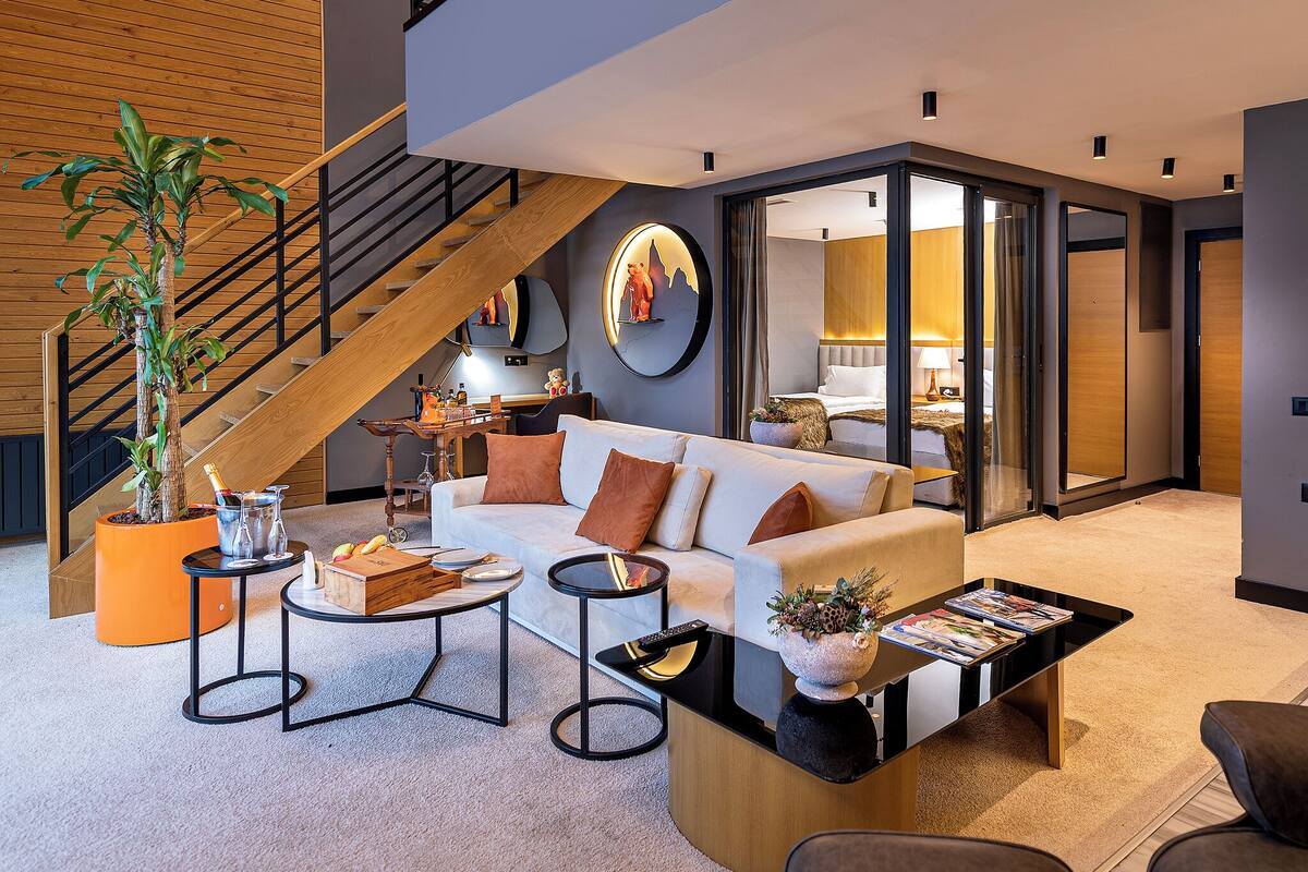Ein modernes Interieur mit Treppe, einem Wohnbereich mit Sofa, Couchtisch und einer Zimmerpflanze.