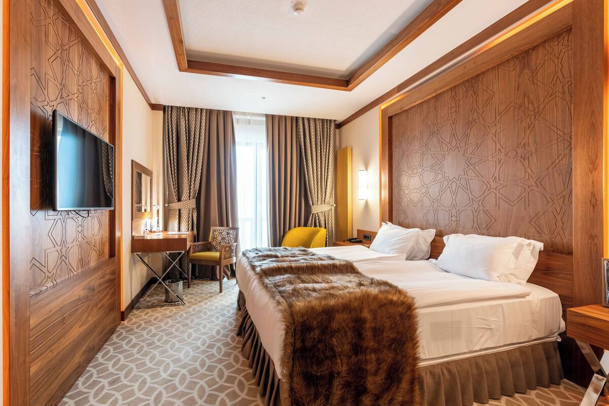 Ein Hotelzimmer mit einem großen Bett, einem Fernseher, einem Schreibtisch mit Stuhl und einer Wand mit Muster.