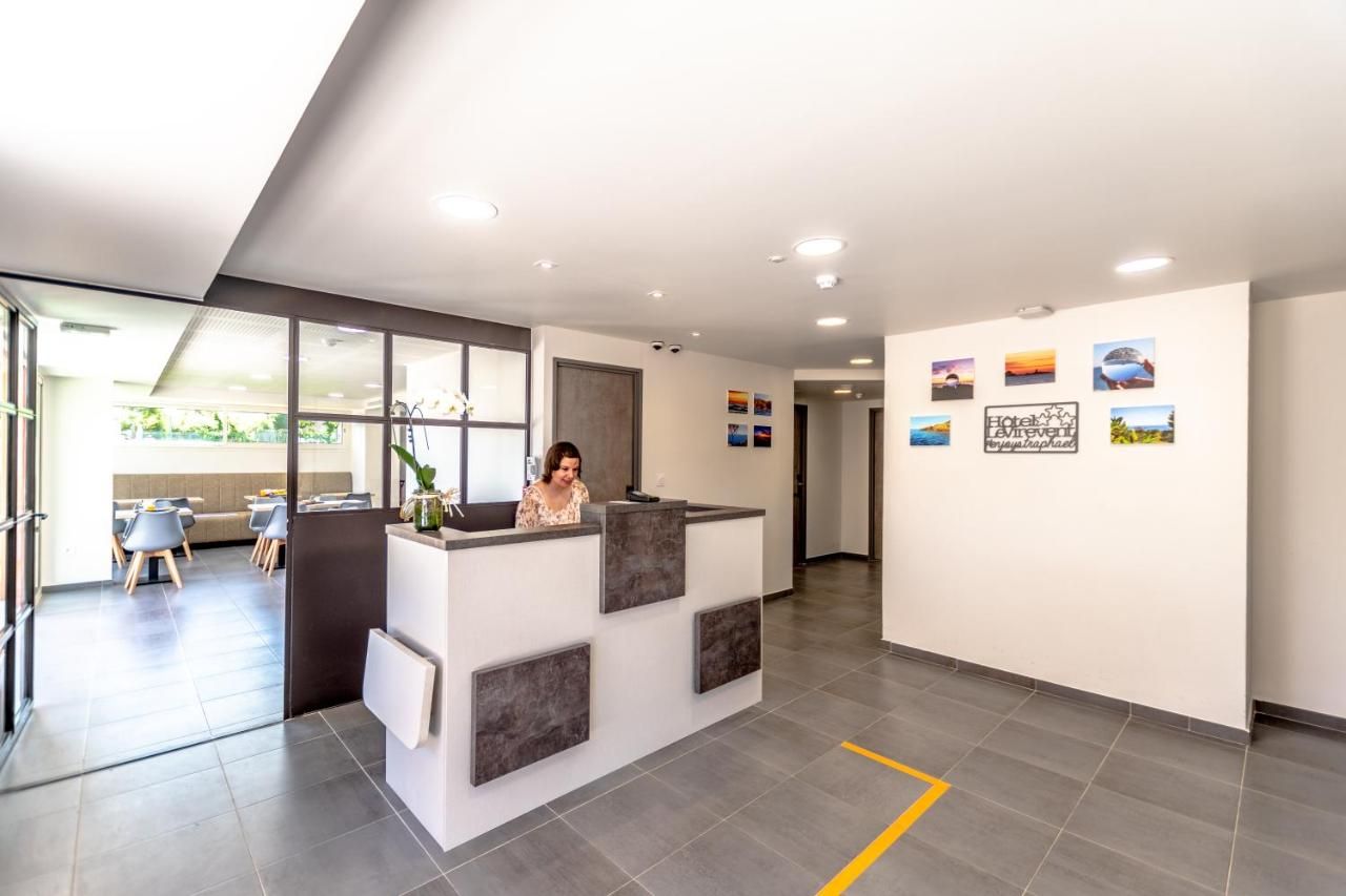 A reception area with a receptionist, a seating area with tables and chairs, and a wall with framed pictures.