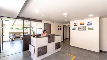 A reception area with a receptionist, a seating area with tables and chairs, and a wall with framed pictures.