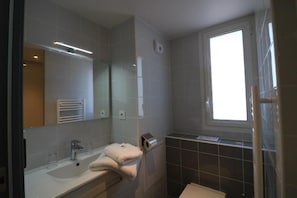 A modern bathroom with a large mirror, a sink, and a window. - Hotel Le Virevent (Saint-Raphael)