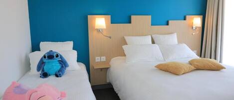Two hotel beds with white bedding, a blue wall, and wall-mounted lamps.
