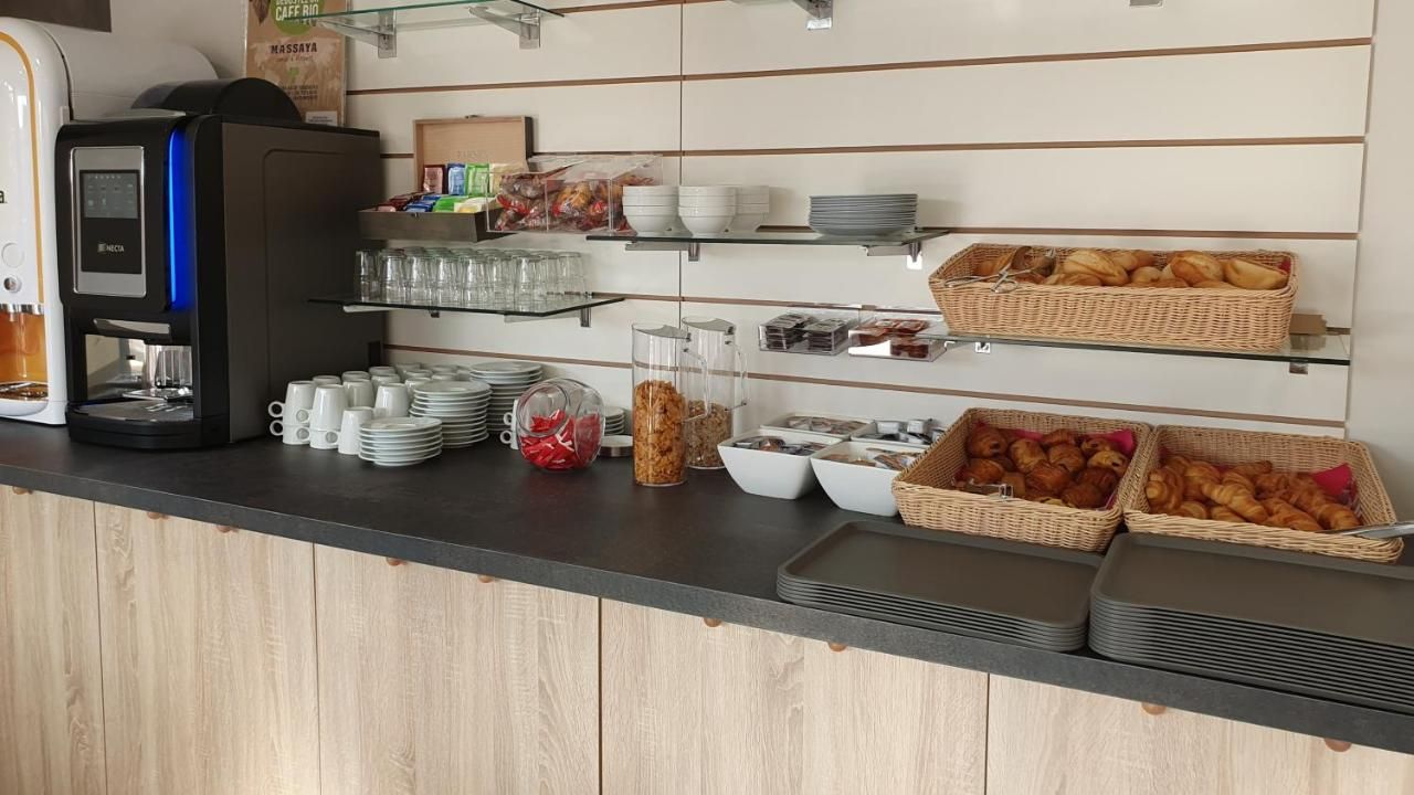 A breakfast bar with coffee machines, glassware, and various food items.