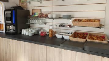 A breakfast bar with coffee machines, glassware, and various food items.