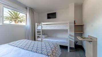 Hotellihuoneessa on kerrossänky, yksi erillinen sänky, seinälle asennettu televisio, pieni työpöytä, jossa on lehti, ja ikkuna, josta avautuu näkymä palmuille.