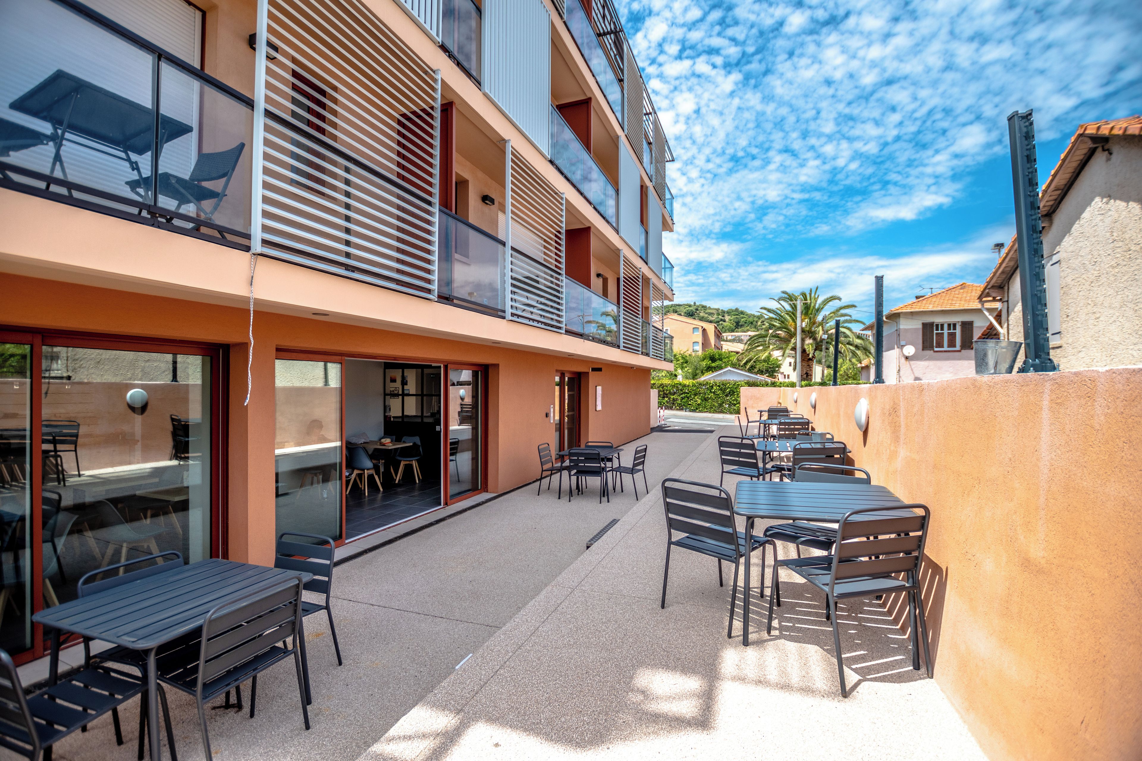 A multi-story building with outdoor seating and a balcony.