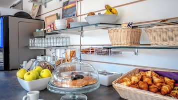 A buffet with various food items, including apples, pastries, and a covered display case.