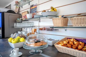 A buffet with various food items, including apples, pastries, and a covered display case. - Hotel Le Virevent (Saint-Raphael)