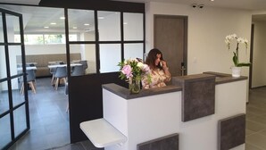 A reception area with a modern design, including a reception desk, seating area, and large windows.