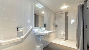 A modern bathroom with a white sink, mirror, and shower.