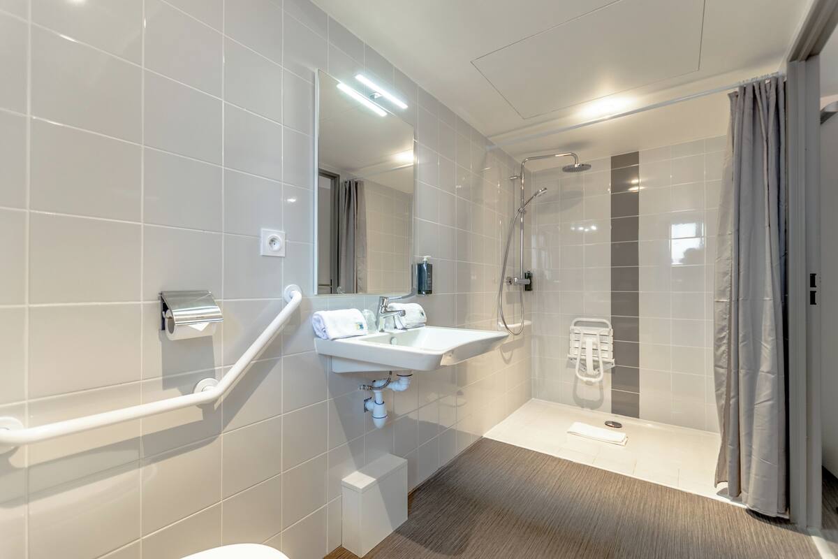 A modern bathroom with a white sink, mirror, and shower.