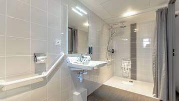 A modern bathroom with a white sink, mirror, and shower.