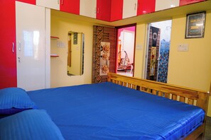 A room with a bed, a wardrobe, and a mirror.