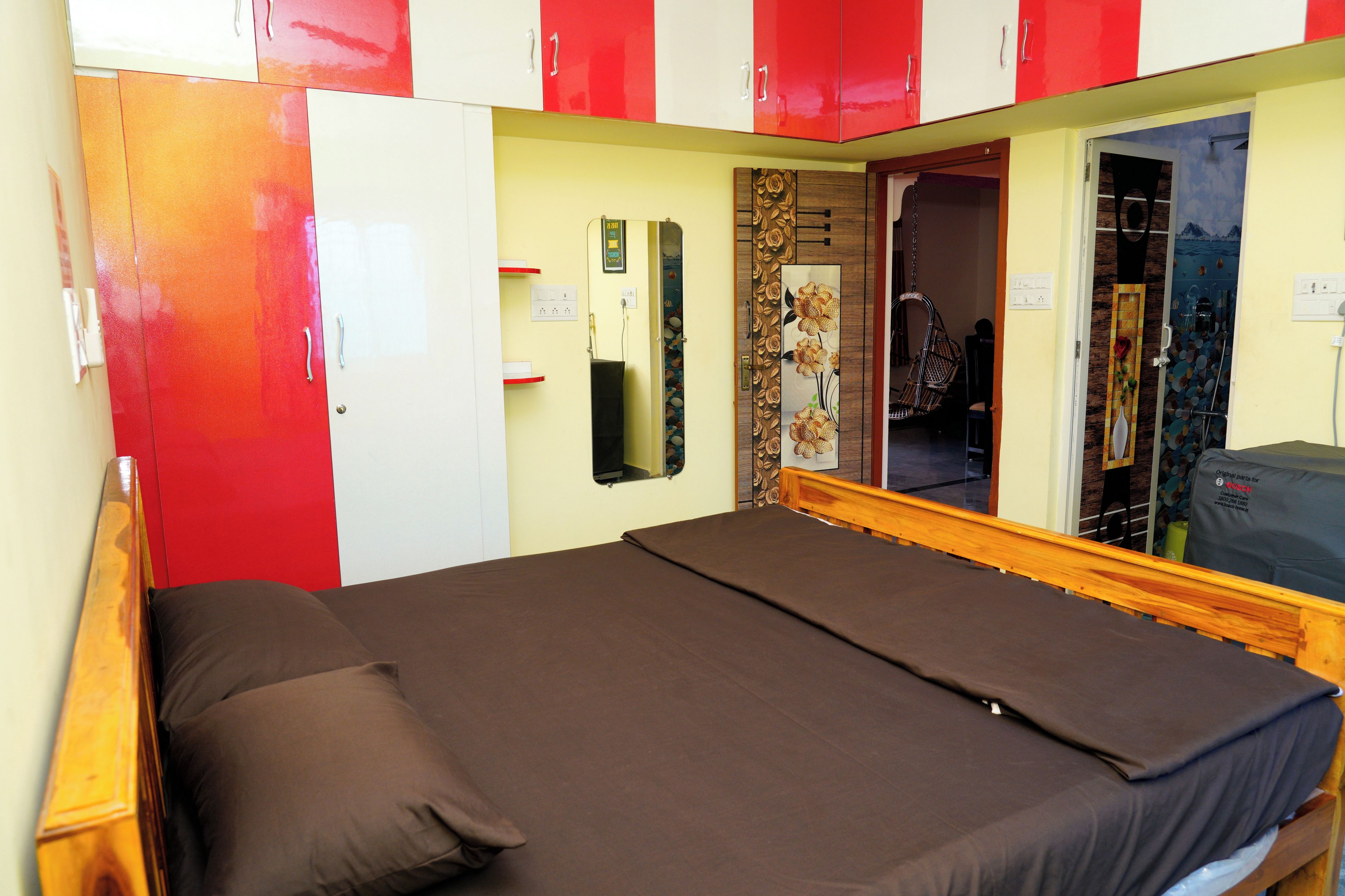 A room with a bed, wardrobe, and a mirror.