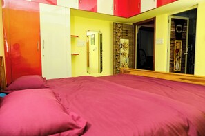 A bedroom with a bed, a wardrobe, a mirror, and a door. - Sri Sakthi Residence (Tiruvannamalai)