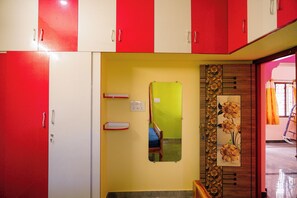 Ein Zimmer mit roten und weißen Schränken, einer grünen Tür und einem Spiegel an der Wand.