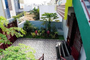 A residential courtyard with a tiled floor, a staircase, and various plants.