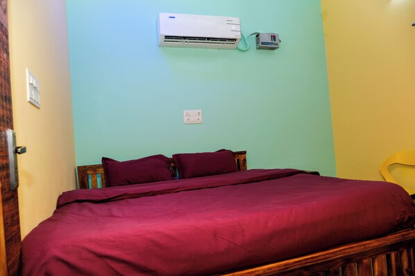 A bedroom with a bed, a wall-mounted air conditioner, and a power outlet.