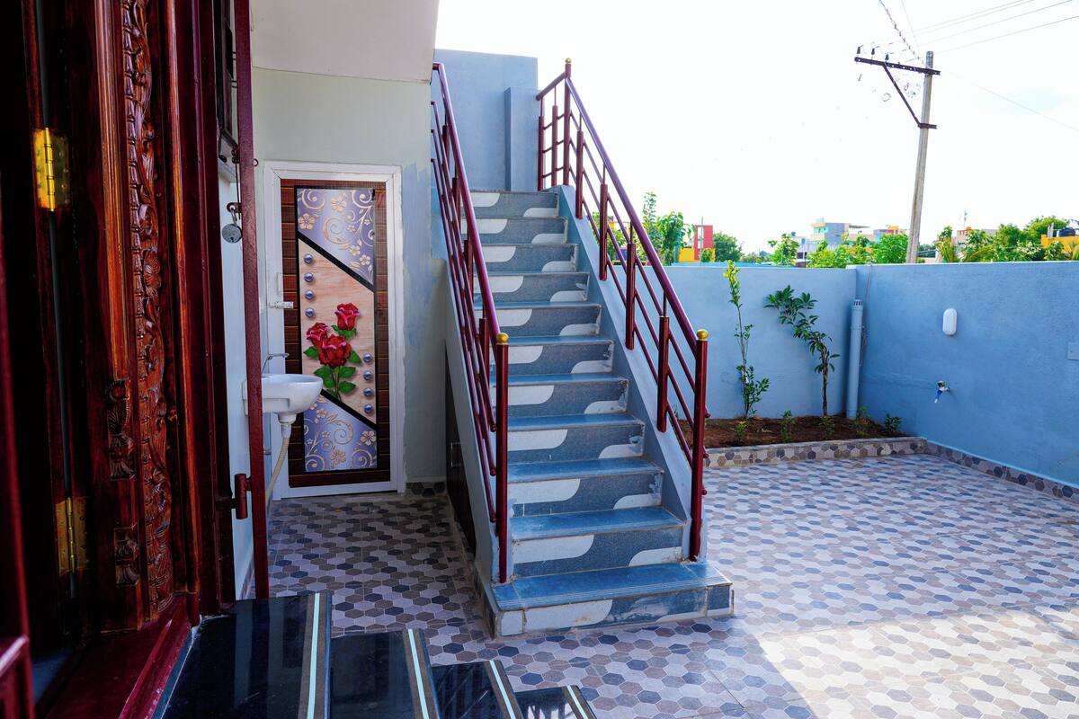 A staircase with a red handrail leading to a door with a floral design.