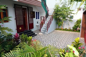 A house with a red door, white walls, and a tiled patio.